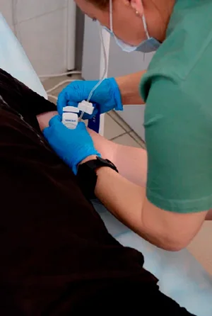 Врач готовит пациента ставить капельницу